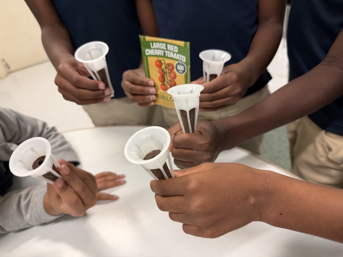 Students holding hydroponic growing cups with seeds