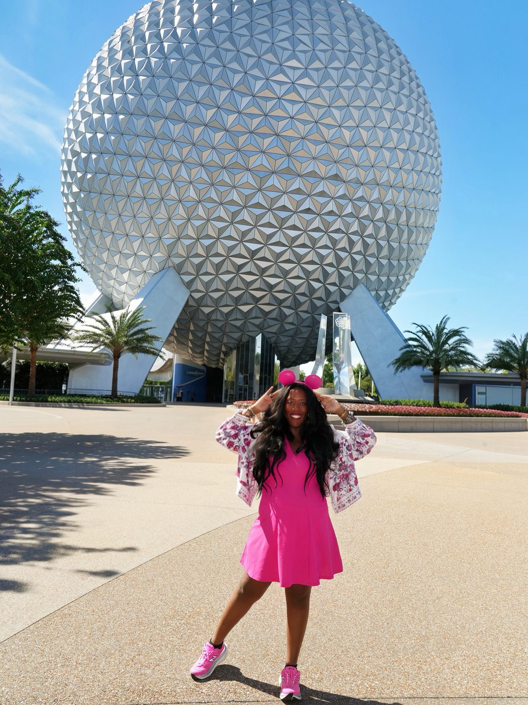 Victoria in a pink dress and Minnie ears in front of Spaceship Earth at Epcot